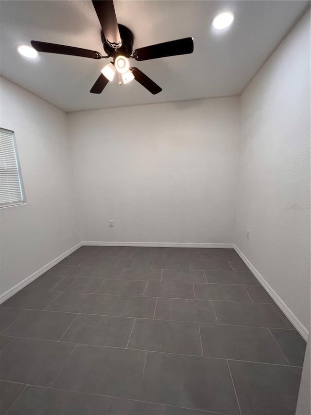 unfurnished room featuring ceiling fan and dark tile patterned flooring