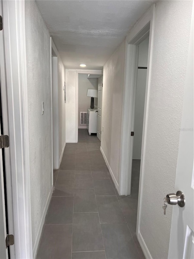 hallway with dark tile patterned floors