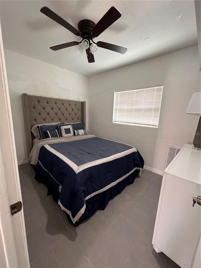 bedroom with dark tile patterned floors and ceiling fan