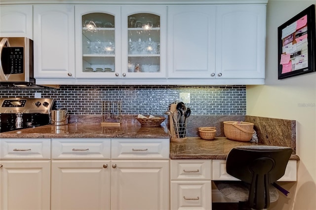 kitchen with decorative backsplash, dark stone counters, and white cabinets