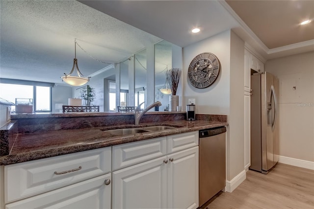 kitchen with appliances with stainless steel finishes, sink, white cabinets, and light wood-type flooring