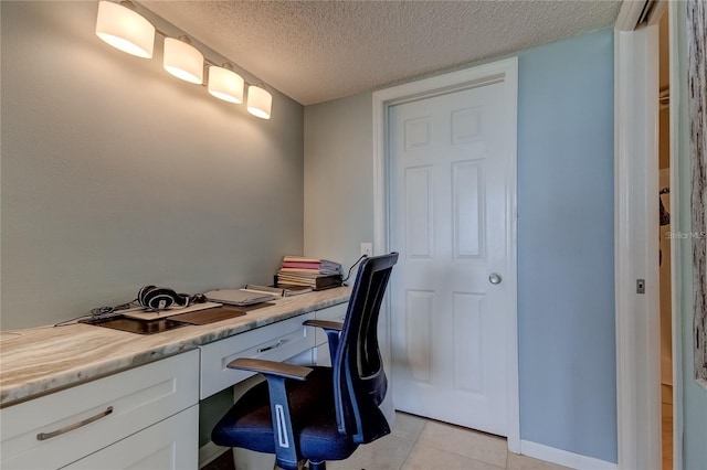 tiled office featuring built in desk and a textured ceiling