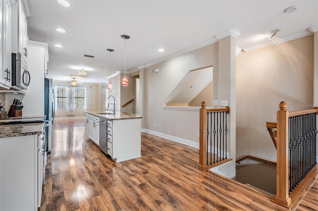 kitchen featuring white cabinets, decorative light fixtures, a center island with sink, and stainless steel appliances