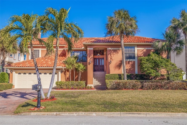 mediterranean / spanish home featuring a garage and a front lawn