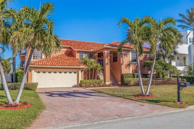 207 8th St E, Tierra Verde, FL 33715 - mediterranean / spanish house featuring a tiled roof, stucco siding, driveway, a front lawn, and an attached garage