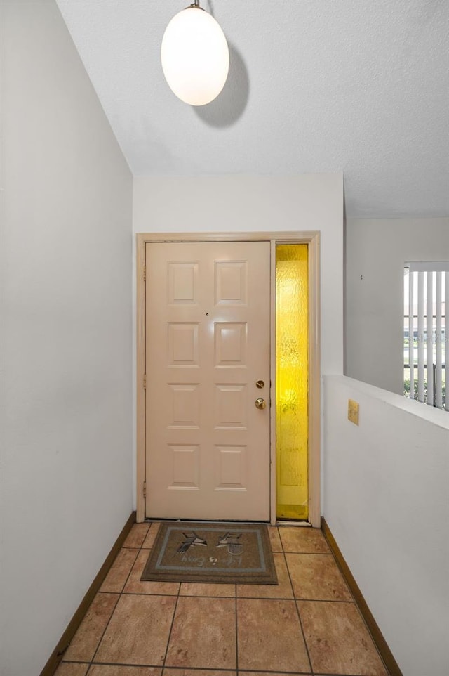 doorway to outside featuring light tile patterned floors and a textured ceiling