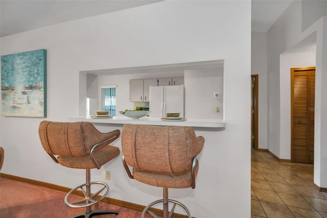 kitchen featuring kitchen peninsula, white refrigerator, and tile patterned flooring