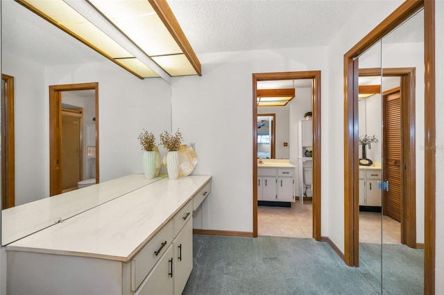 hallway with a textured ceiling, light colored carpet, and sink