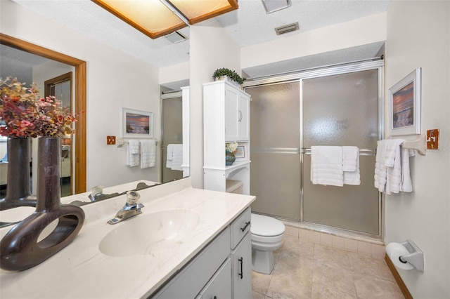 bathroom with vanity, a textured ceiling, toilet, and a shower with door