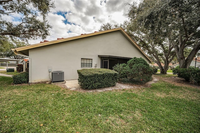 view of side of home with a yard and central AC unit