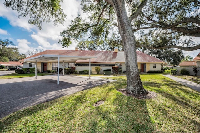 ranch-style house with a carport and a front lawn