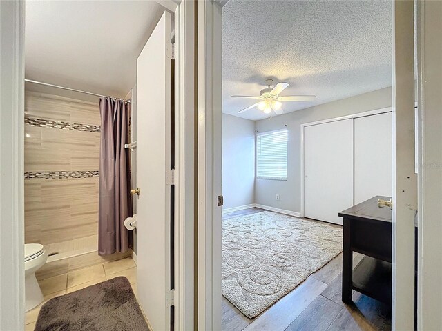 bathroom with a shower with curtain, toilet, and ceiling fan