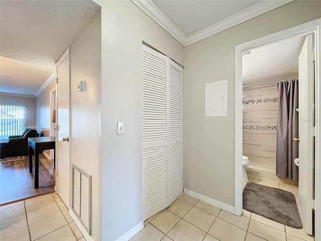 hall featuring light tile patterned floors, a textured ceiling, and ornamental molding