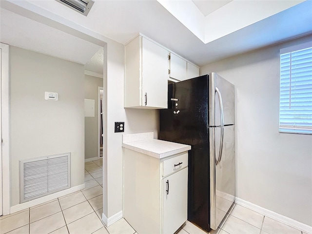 kitchen featuring white cabinets, light tile patterned flooring, and stainless steel refrigerator