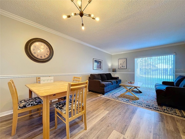 dining room featuring a textured ceiling, light hardwood / wood-style flooring, and ornamental molding