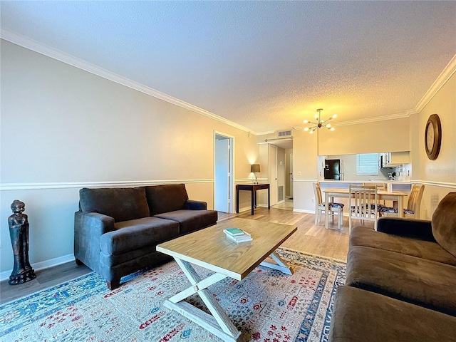 living room featuring hardwood / wood-style floors, a textured ceiling, crown molding, and an inviting chandelier