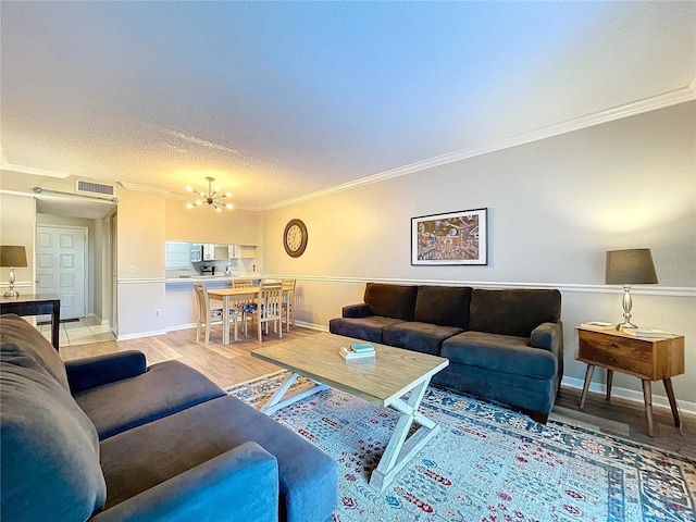 living room with a chandelier, light wood-type flooring, and crown molding