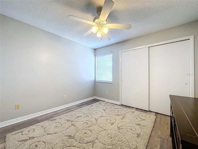 unfurnished bedroom featuring hardwood / wood-style floors, a textured ceiling, a closet, and ceiling fan