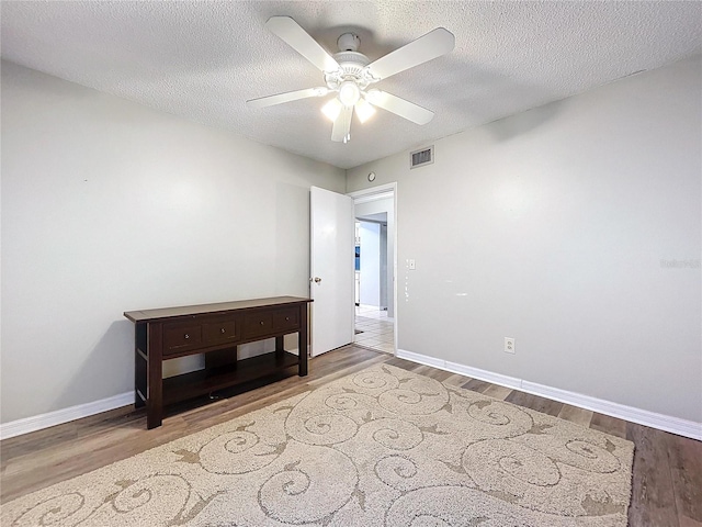 unfurnished room with ceiling fan, wood-type flooring, and a textured ceiling