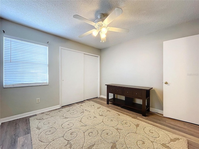 bedroom with ceiling fan, wood-type flooring, a textured ceiling, and a closet