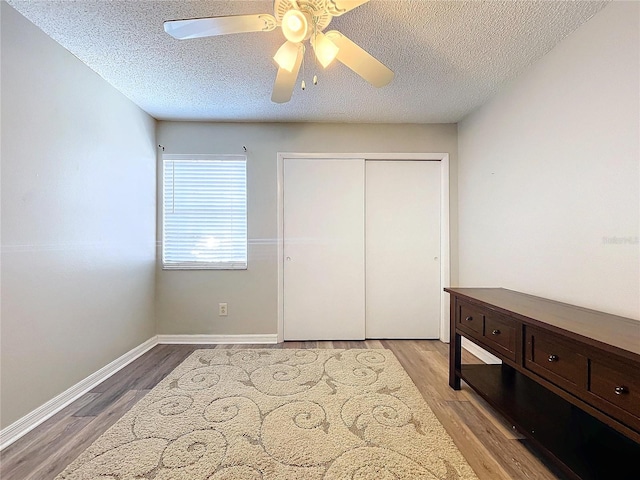 bedroom with ceiling fan, a closet, a textured ceiling, and light wood-type flooring