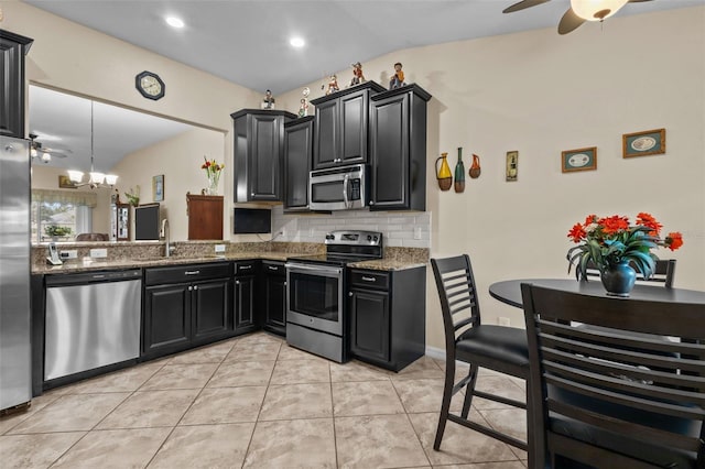 kitchen with stone counters, sink, stainless steel appliances, tasteful backsplash, and vaulted ceiling