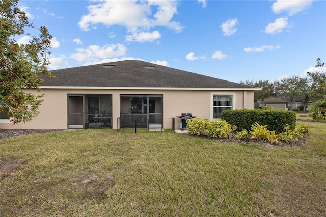 rear view of property featuring a sunroom and a yard