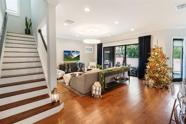 living room featuring hardwood / wood-style floors, a healthy amount of sunlight, ornamental molding, and a chandelier