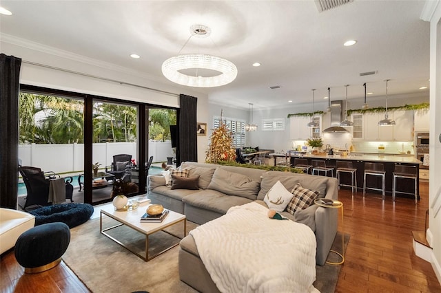 living room featuring a notable chandelier, dark hardwood / wood-style flooring, and crown molding