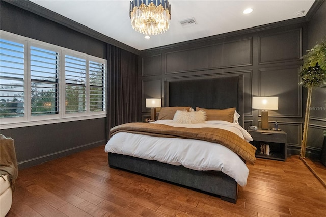 bedroom with dark hardwood / wood-style floors, an inviting chandelier, and crown molding