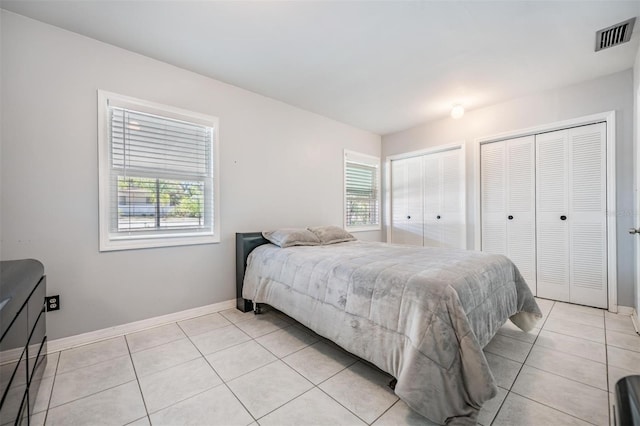 tiled bedroom featuring two closets