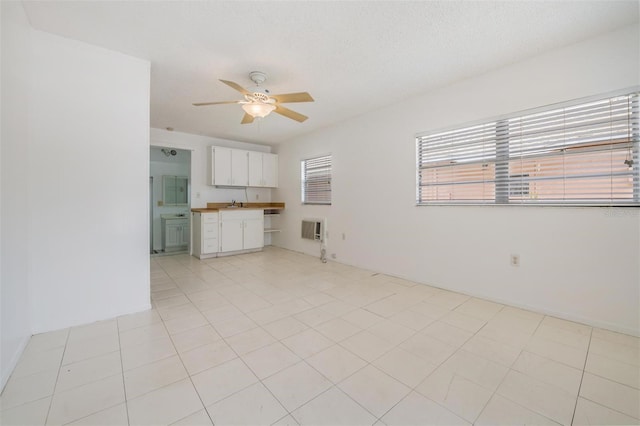 unfurnished living room featuring ceiling fan, sink, heating unit, a textured ceiling, and light tile patterned floors