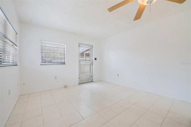 tiled empty room featuring ceiling fan and a textured ceiling