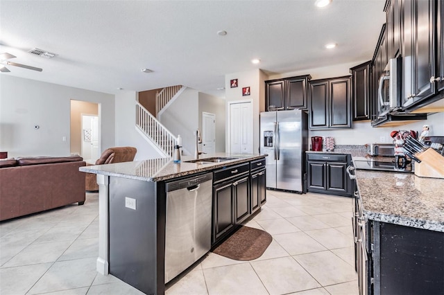 kitchen with light stone counters, a center island with sink, sink, and appliances with stainless steel finishes