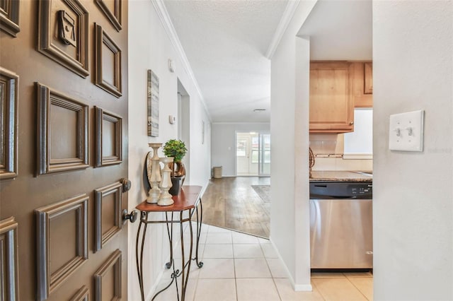 tiled foyer with ornamental molding and a textured ceiling