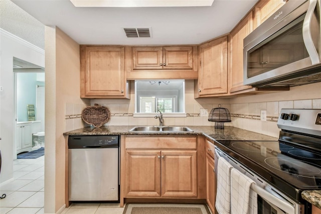 kitchen featuring sink, dark stone countertops, stainless steel appliances, and light tile patterned flooring