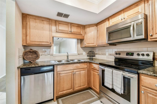 kitchen featuring sink, tasteful backsplash, dark stone countertops, and stainless steel appliances