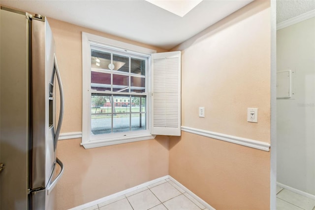 interior space with crown molding, a textured ceiling, stainless steel fridge with ice dispenser, and light tile patterned floors