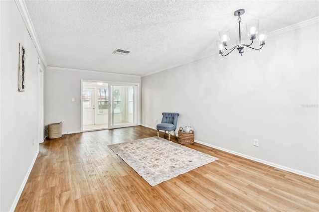 unfurnished room with crown molding, light hardwood / wood-style floors, a textured ceiling, and an inviting chandelier