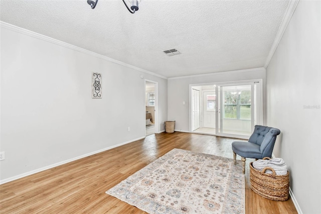 living area featuring wood-type flooring, a textured ceiling, and ornamental molding