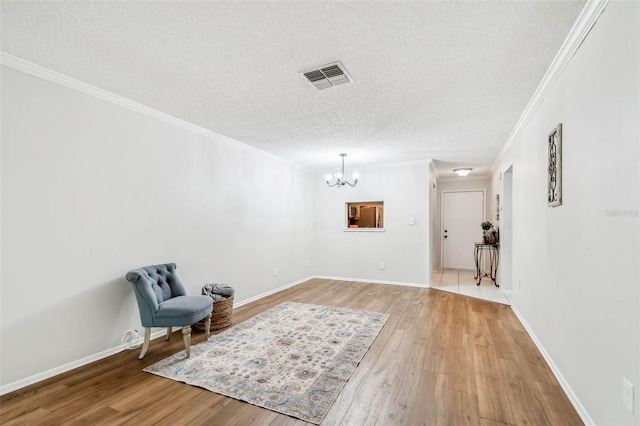 living area with a notable chandelier, hardwood / wood-style flooring, crown molding, and a textured ceiling