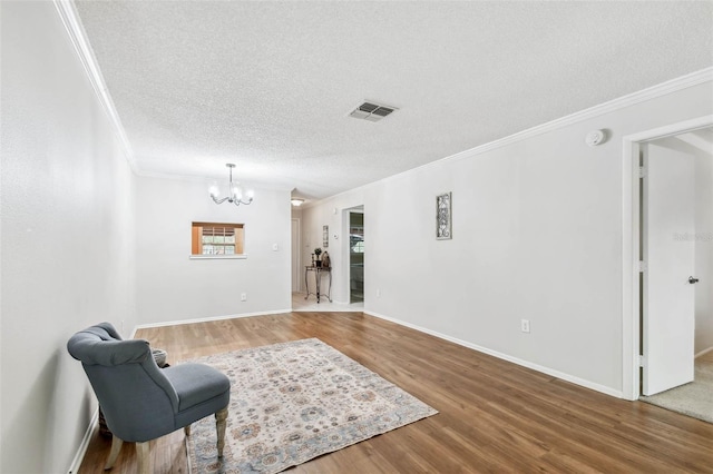 sitting room with crown molding, hardwood / wood-style flooring, a textured ceiling, and a chandelier