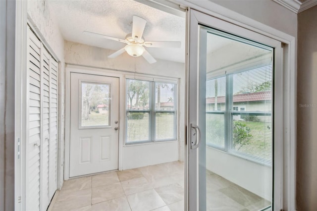 doorway to outside with ceiling fan, light tile patterned floors, and a textured ceiling