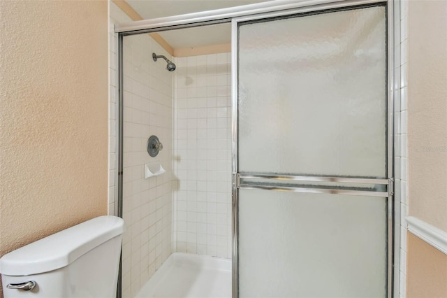 bathroom featuring a shower with shower door and toilet