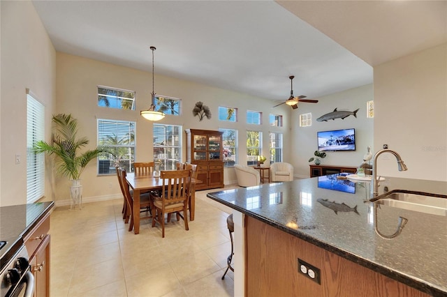 kitchen featuring a healthy amount of sunlight, pendant lighting, dark stone counters, and a sink