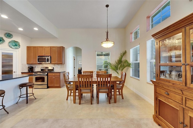 dining area with recessed lighting, plenty of natural light, baseboards, and arched walkways