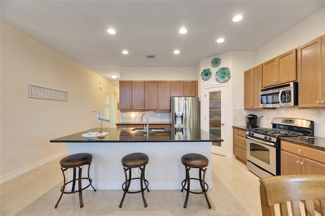 kitchen featuring a kitchen bar, stainless steel appliances, a kitchen island with sink, and sink