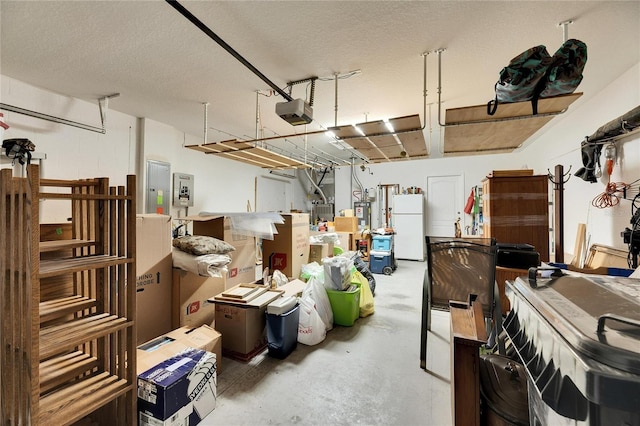 garage featuring gas water heater, white refrigerator, electric panel, and a garage door opener