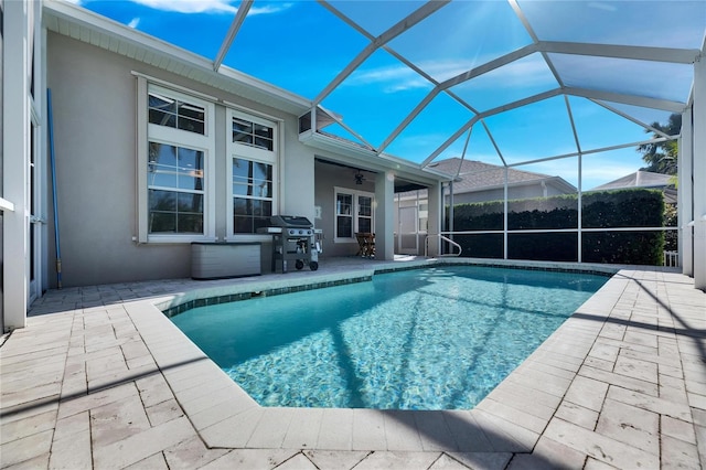 view of pool featuring area for grilling, ceiling fan, a patio area, and glass enclosure