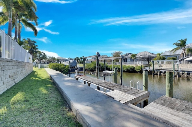 view of dock with a water view and a lawn